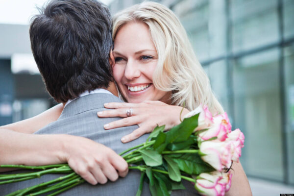 счастливая женщина с цветами обнимает мужчину
